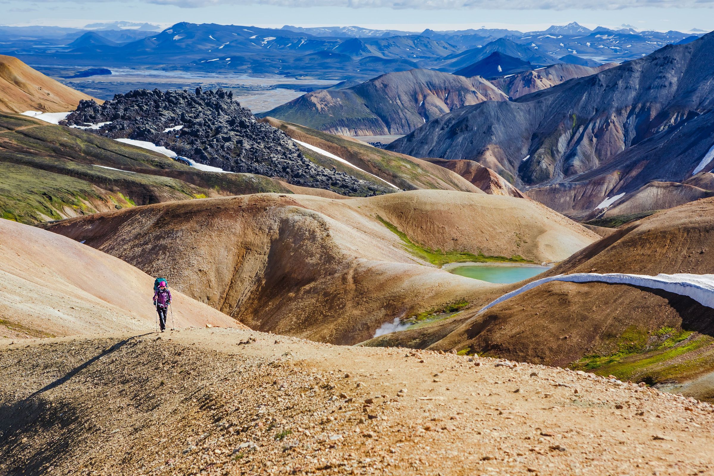 a person is walking on a dirt road in the mountains .