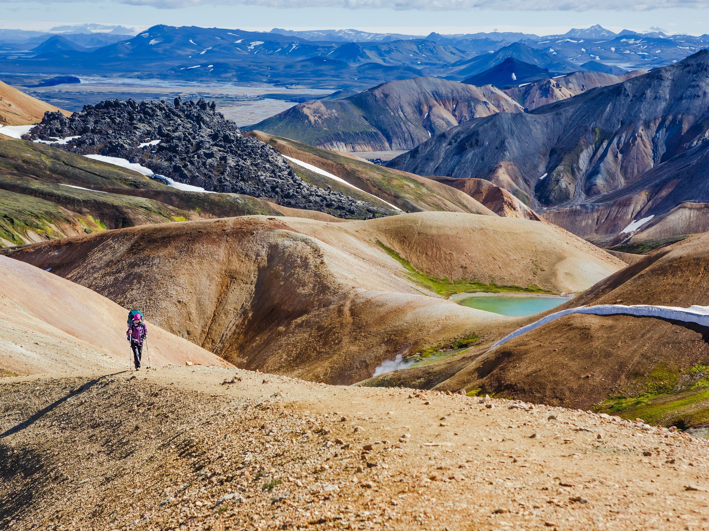 a person is walking on a dirt road in the mountains .