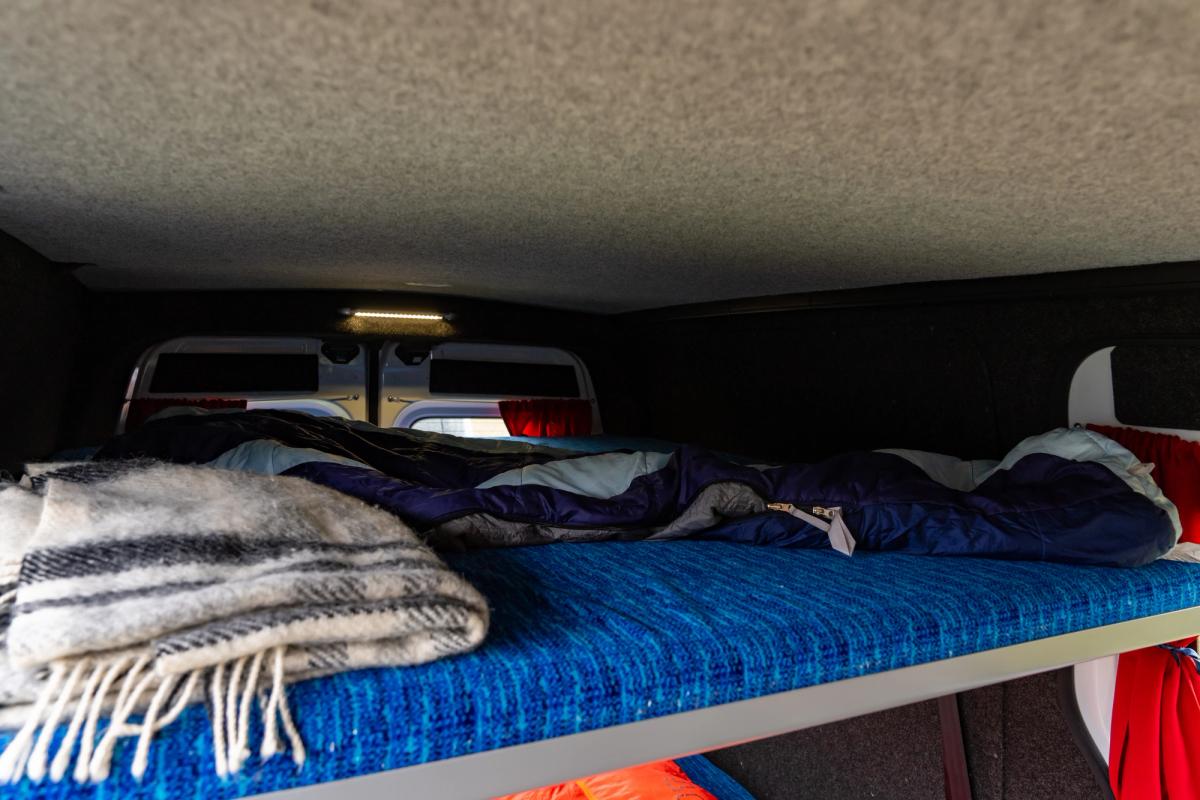 Sleeping bag and fringed blanket on the upper bed of a 5 person large camper