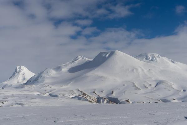 Snowy mountain range under a partly cloudy sky.