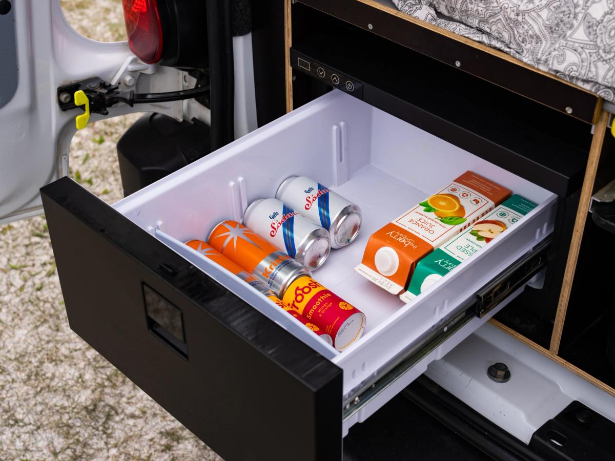 Cajón del frigorífico abierto Cajón frigorífico extraíble abierto, con latas de bebidas y cartones de zumo bajo la plataforma de la cama