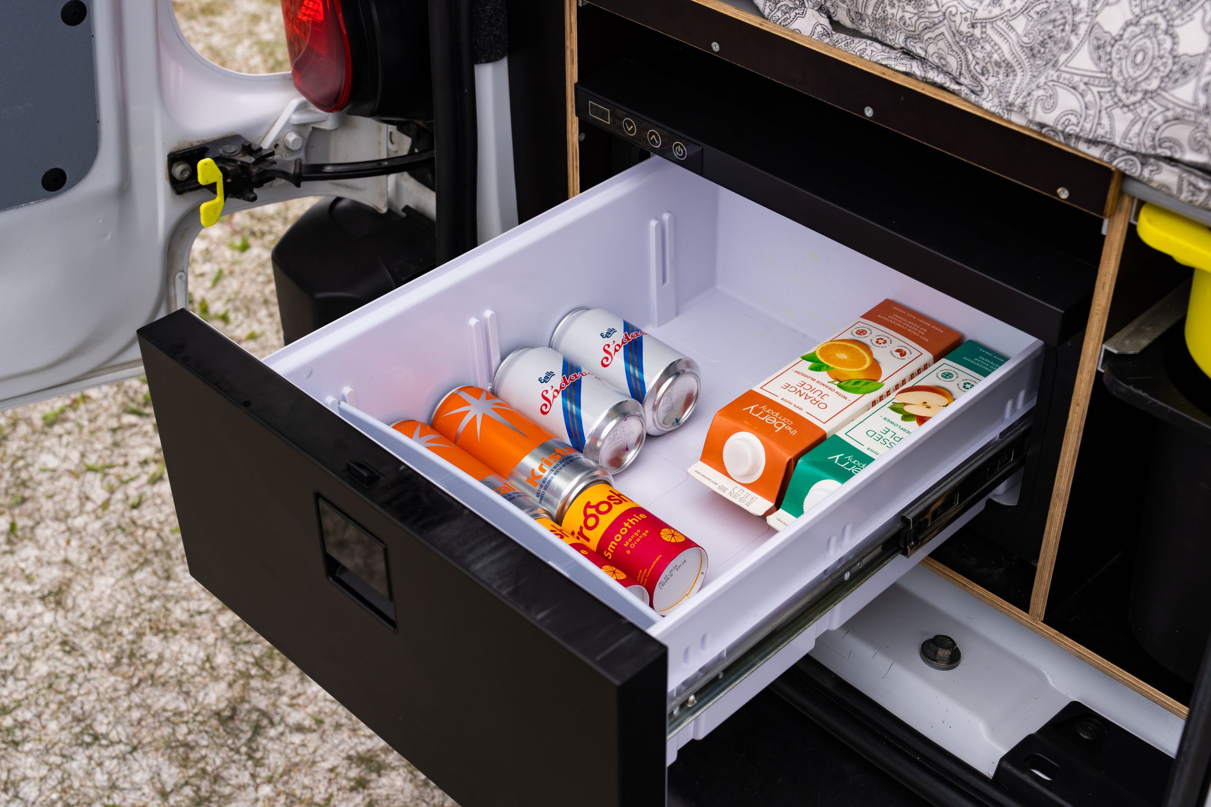 Cajón del frigorífico abierto Cajón frigorífico extraíble abierto, con latas de bebidas y cartones de zumo bajo la plataforma de la cama