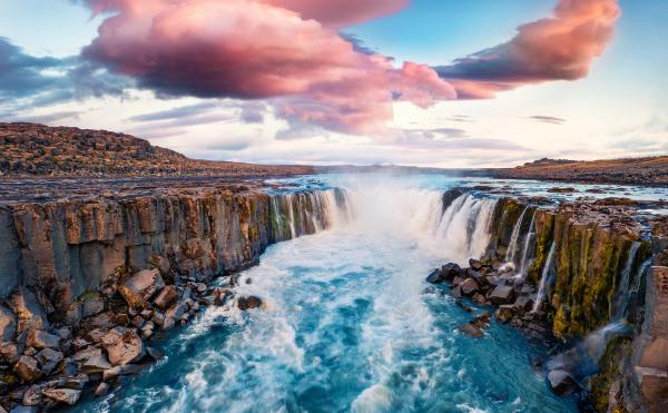 a waterfall in the middle of a river surrounded by rocks .
