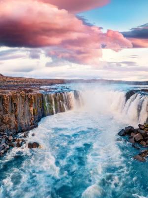 una cascada en medio de un río rodeada de rocas.