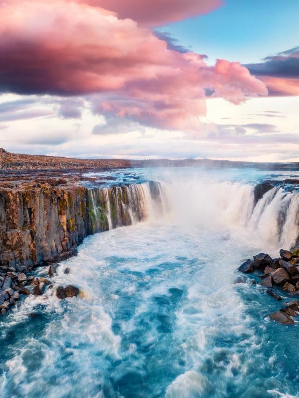 una cascada en medio de un río rodeada de rocas.