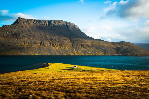 there is a small house on a small island in the middle of a lake with a mountain in the background, Iceland's Westfjords