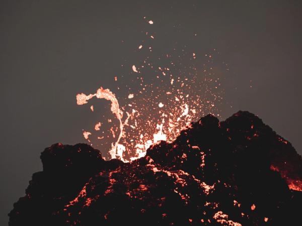 a volcano is erupting and lava is coming out of it .