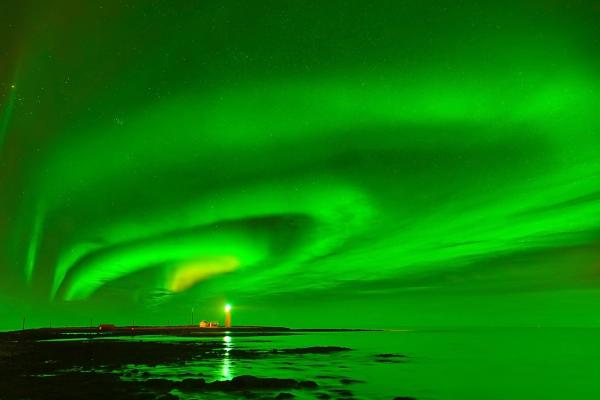Northern Lights at the grotta lighthouse, Reykjavik view on particularly visible green aurora borealis and the grotta lighthouse lit in the distance