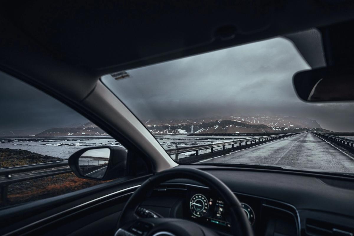 man driving in iceland, the hand on the wheel and the snowy icelandic landscape in the background 