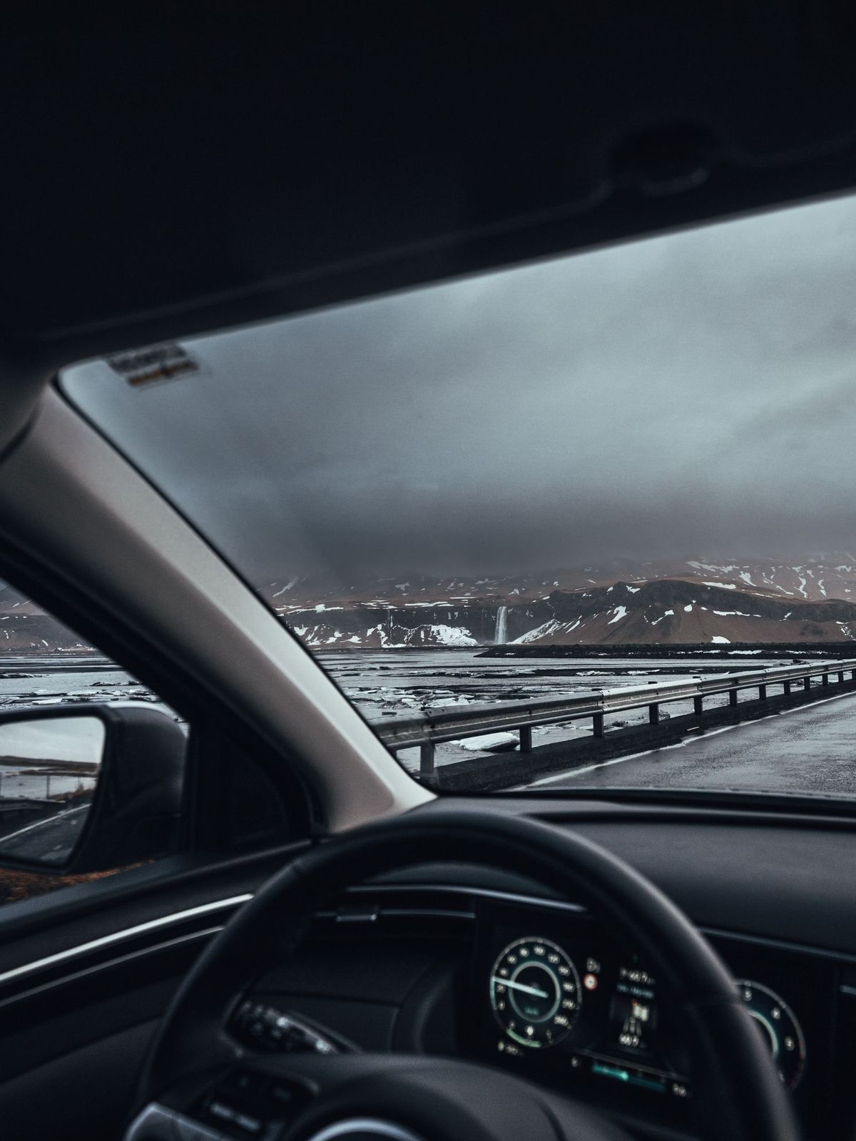 Driving in Iceland man driving in iceland, the hand on the wheel and the snowy icelandic landscape in the background