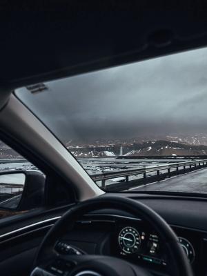 Driving in Iceland  man driving in iceland, the hand on the wheel and the snowy icelandic landscape in the background