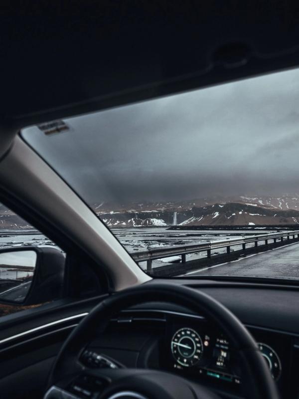Driving in Iceland  man driving in iceland, the hand on the wheel and the snowy icelandic landscape in the background