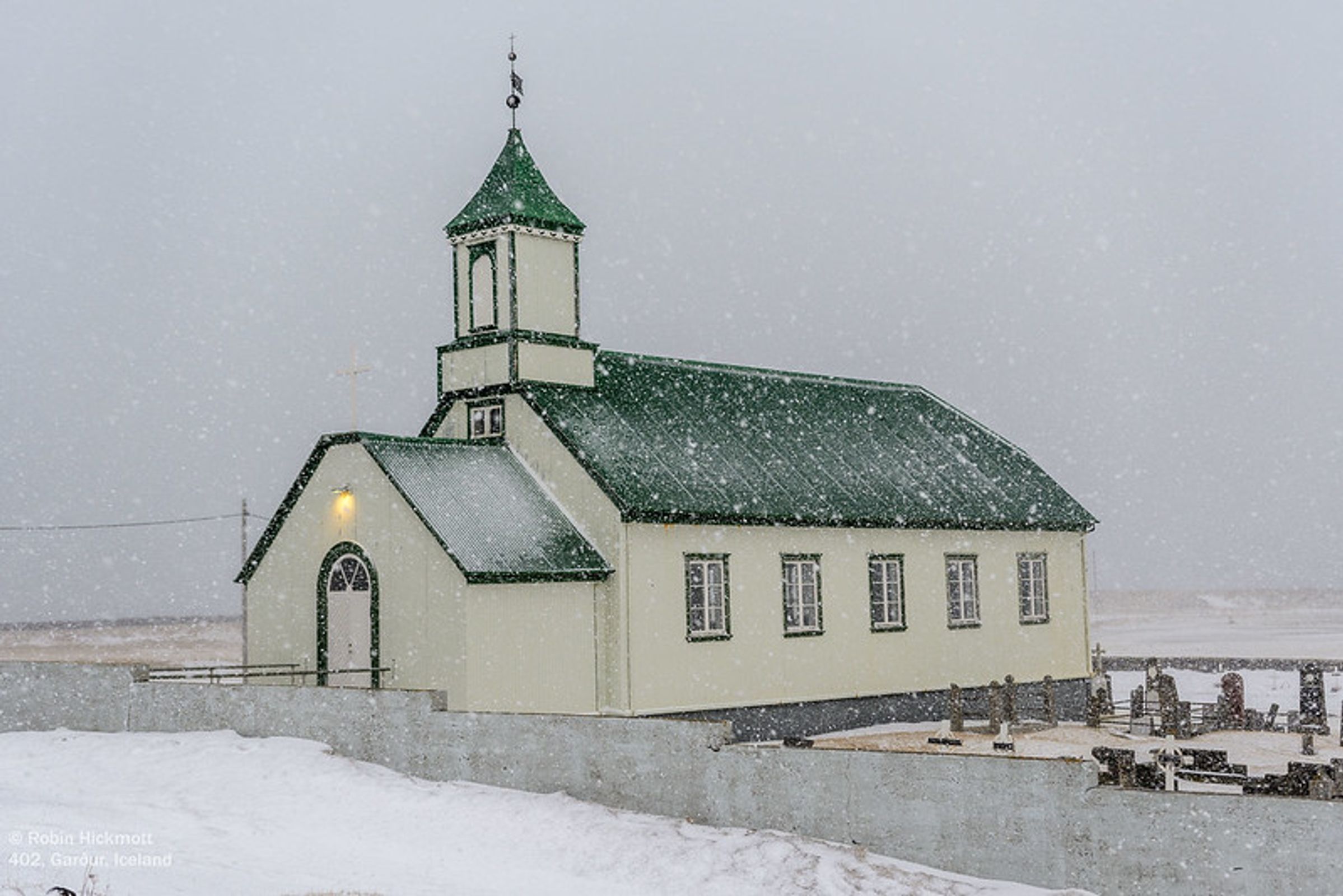 una iglesia verde y blanca en una tormenta de nieve