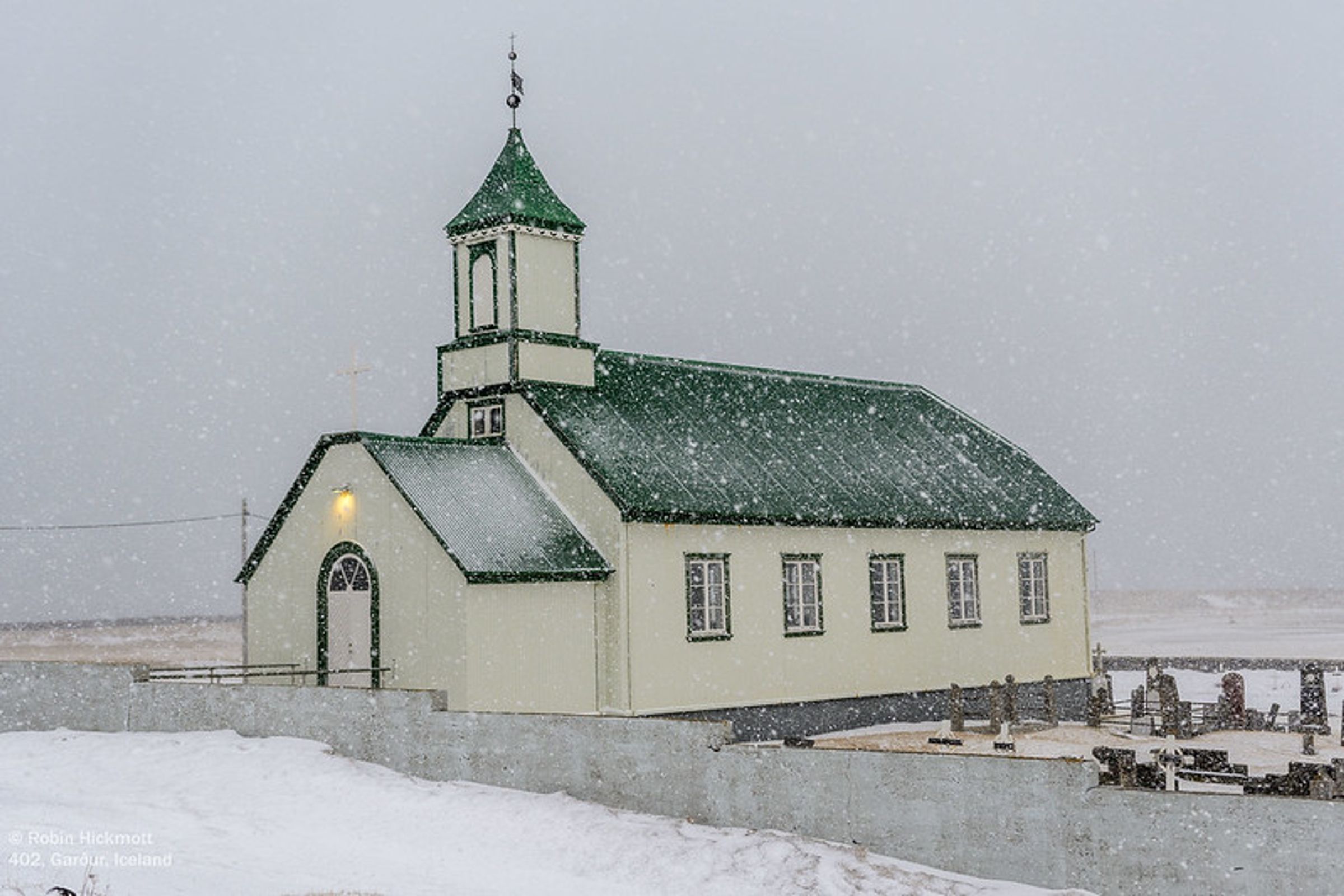 una iglesia verde y blanca en una tormenta de nieve