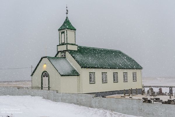 una iglesia verde y blanca en una tormenta de nieve
