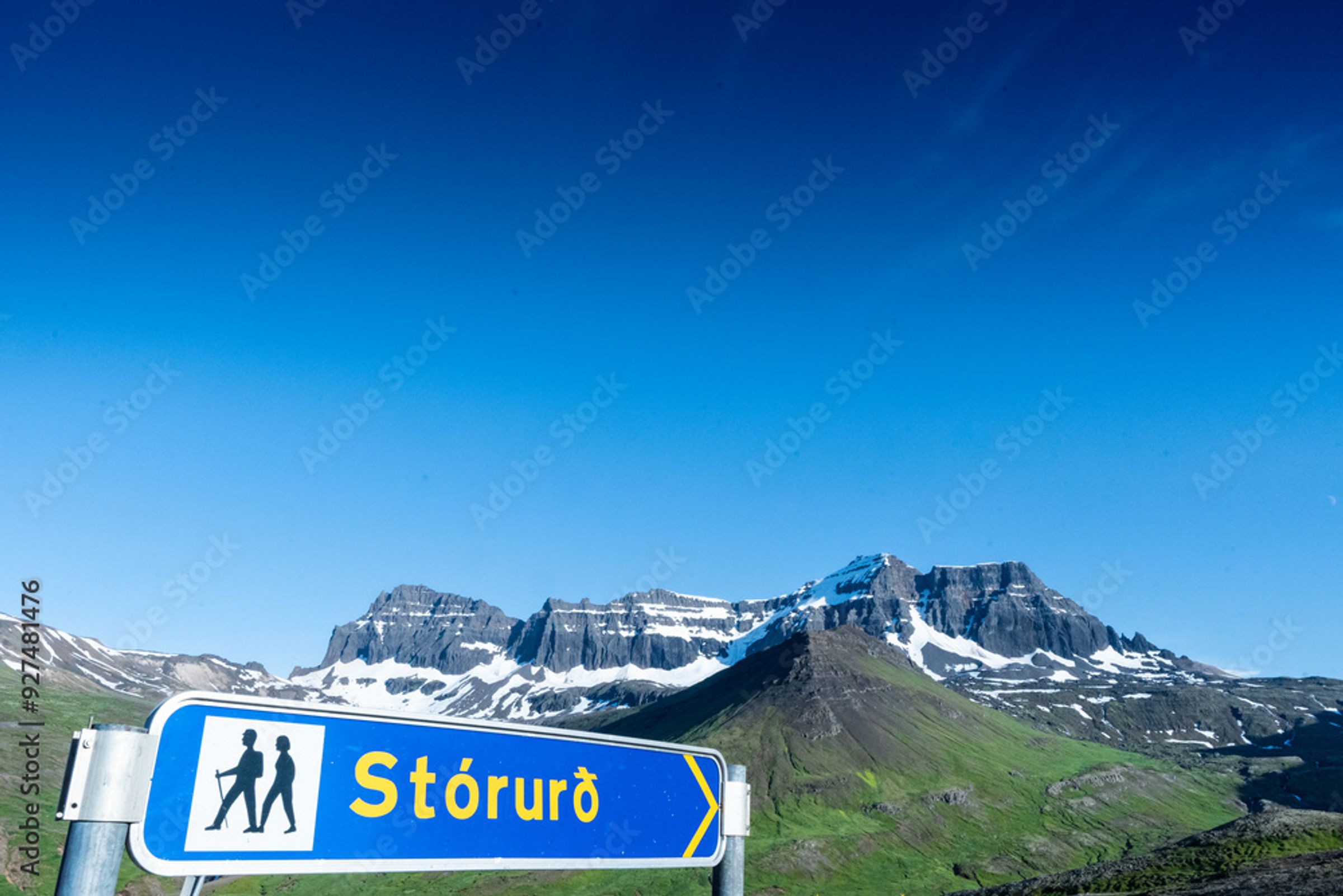 una señal azul con dos personas caminando sobre ella frente a una montaña.