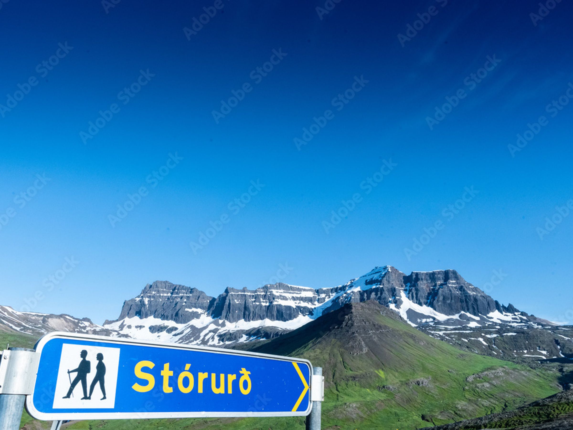 una señal azul con dos personas caminando sobre ella frente a una montaña.