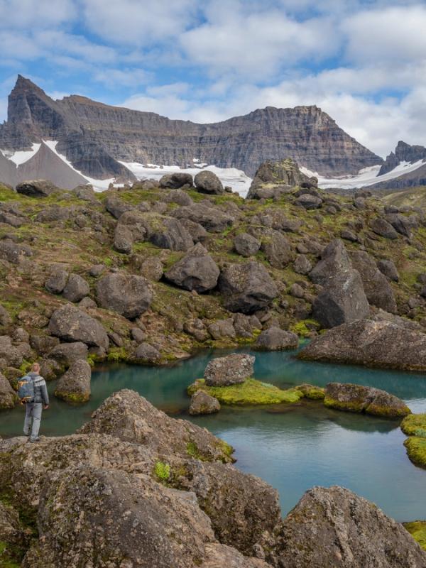 un hombre está parado sobre una roca cerca de un lago en las montañas .