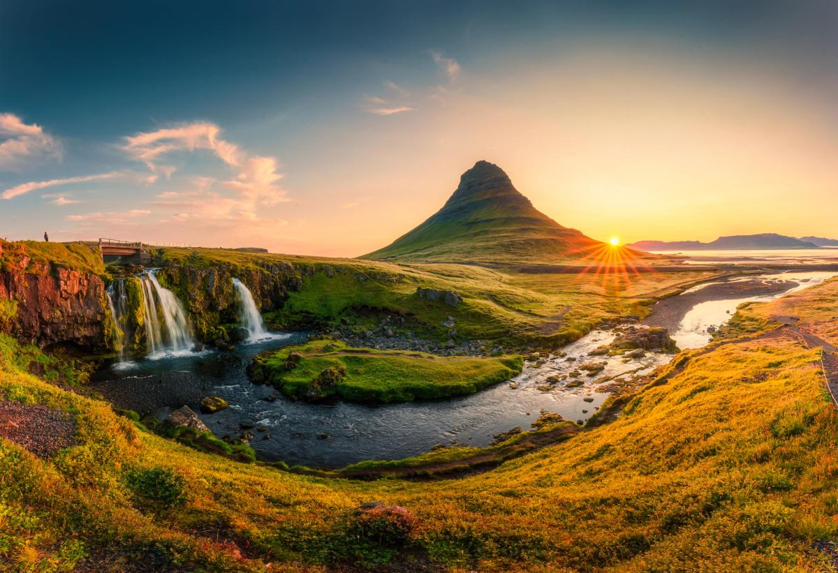 A vibrant sunset over Kirkjufell mountain, with Kirkjufellsfoss waterfall and a river in the foreground.