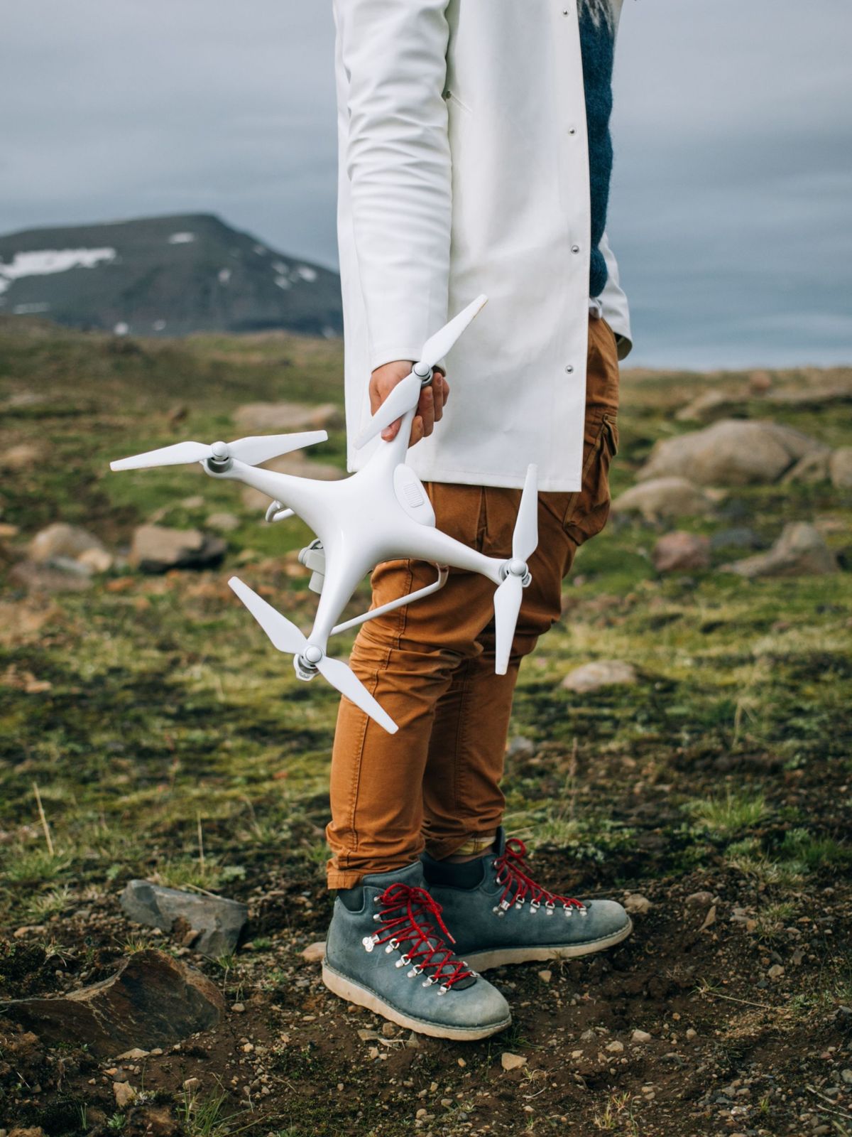 Un hombre se encuentra sobre una superficie rocosa en Islandia durante un viaje épico, sosteniendo un gran dron profesional.
