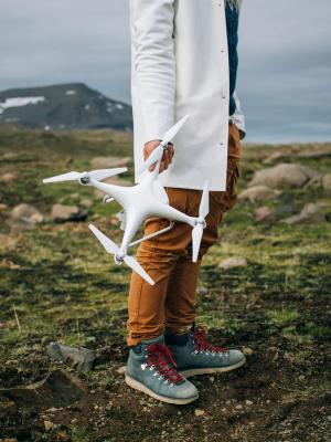 Un hombre se encuentra sobre una superficie rocosa en Islandia durante un viaje épico, sosteniendo un gran dron profesional.