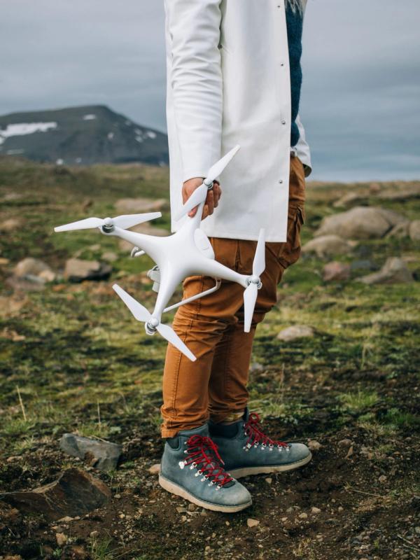 Un hombre se encuentra sobre una superficie rocosa en Islandia durante un viaje épico, sosteniendo un gran dron profesional.