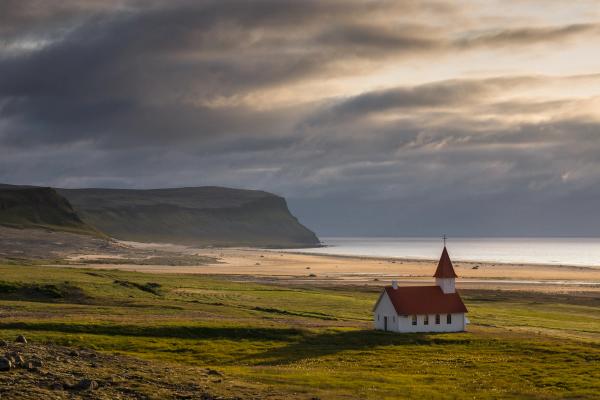 paisaje de una gran playa con una iglesia de color blanco y rojo en primer plano