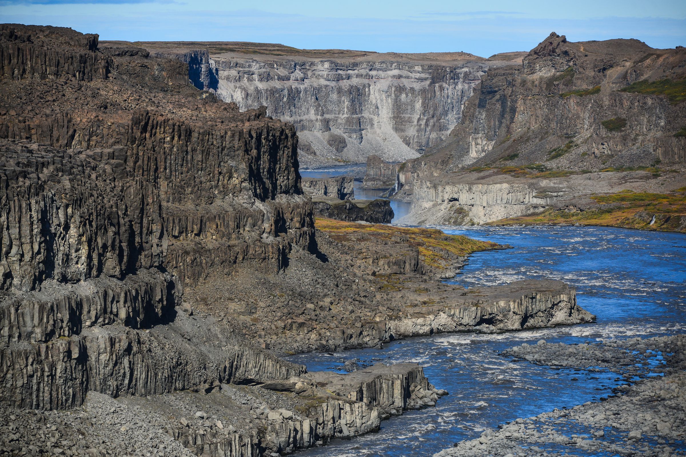 a river flowing through a canyon with a waterfall in the background, Vatnajökull National Park