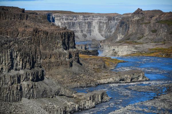 a river flowing through a canyon with a waterfall in the background, Vatnajökull National Park