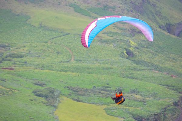 a person is parasailing over a green field, Iceland