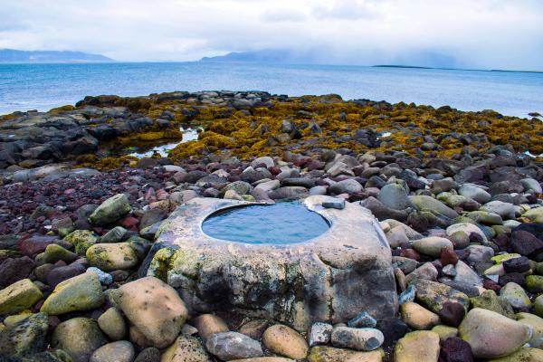 a rocky beach with a pool of water in the middle of it .