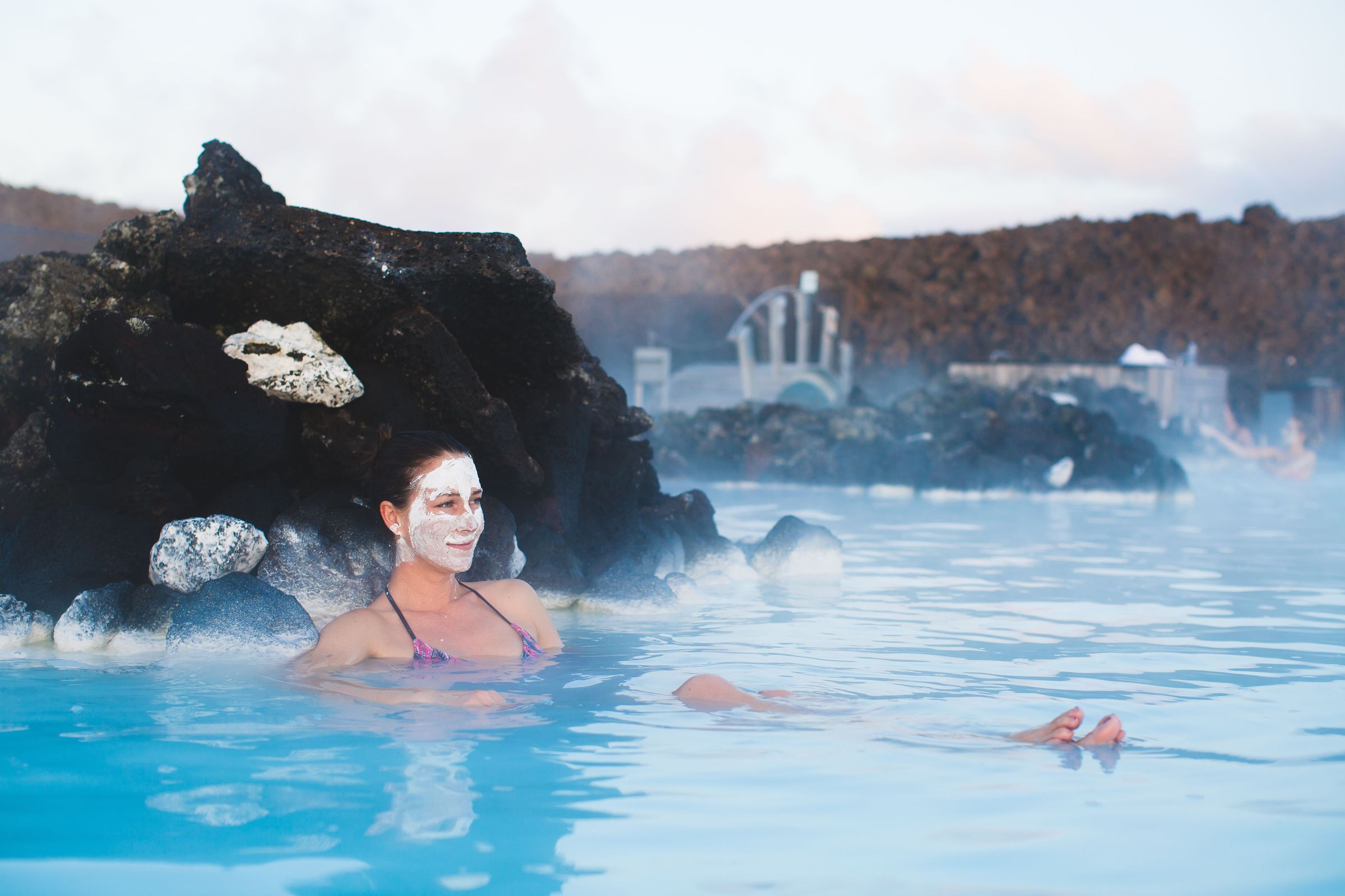 a woman with a face mask is swimming in a hot spring .