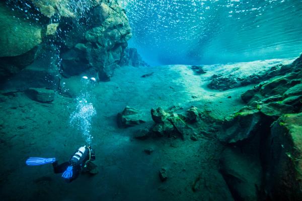 un buzo está nadando en una cueva en el océano .