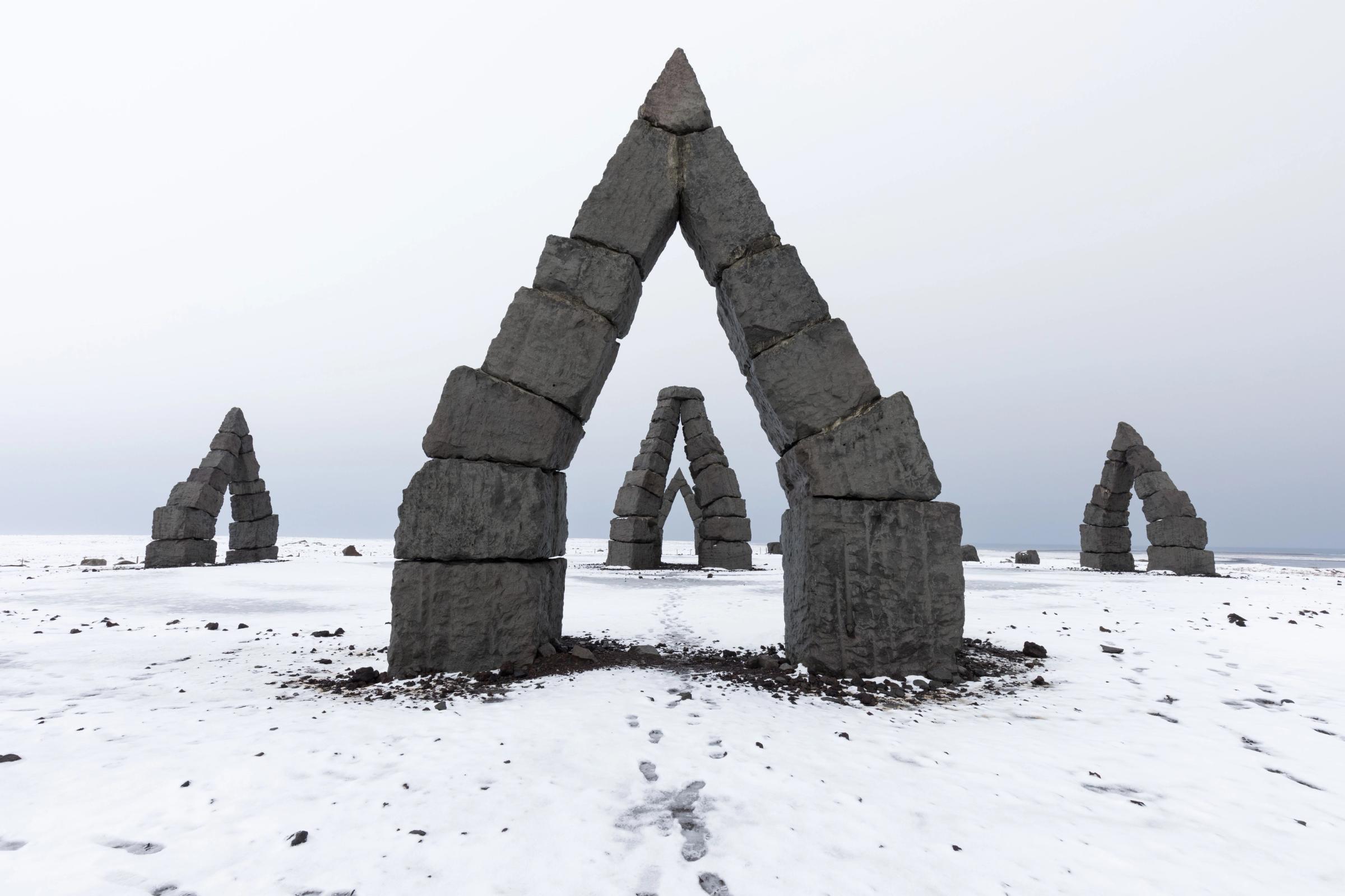 un grupo de arcos de piedra situados en medio de un campo cubierto de nieve.