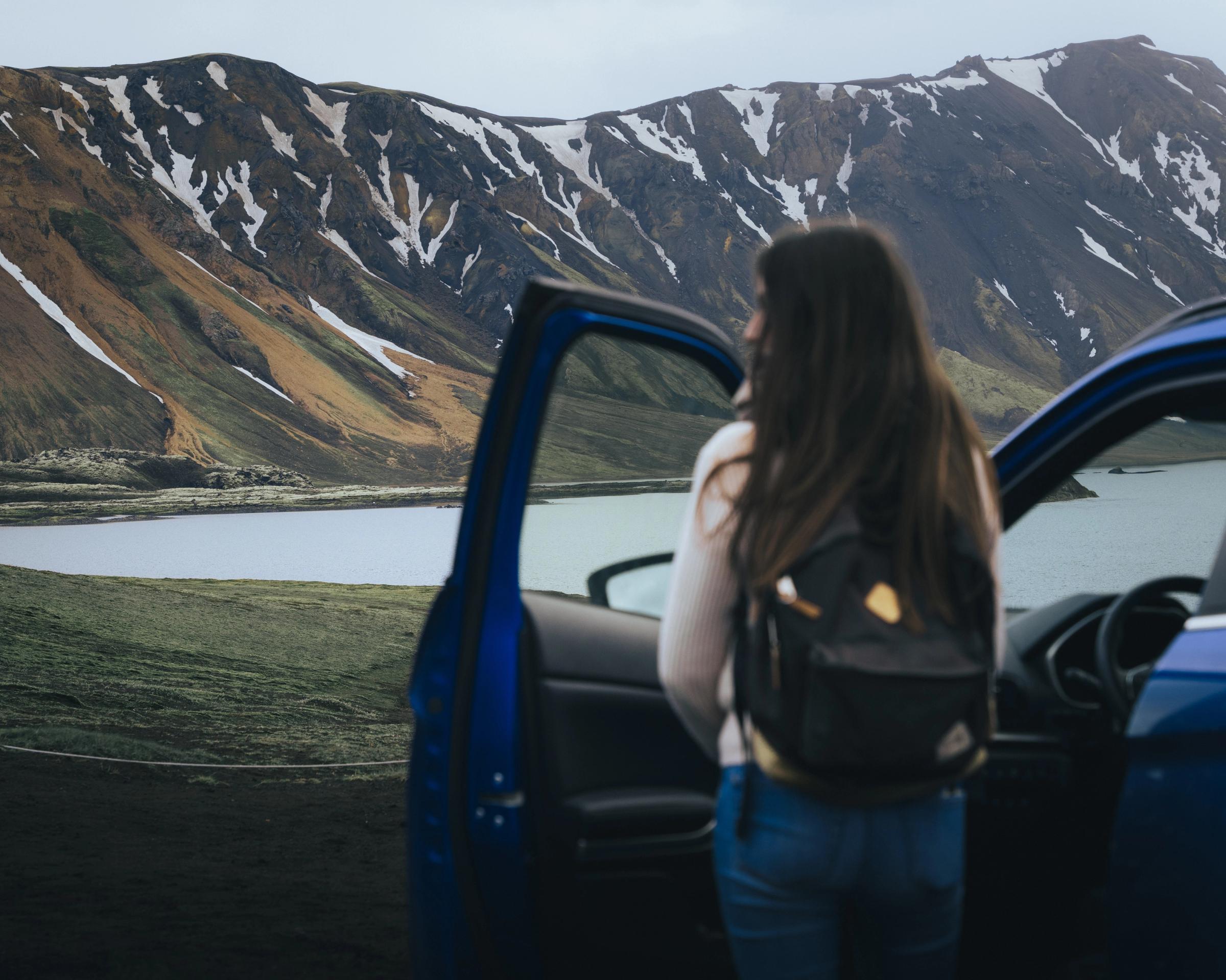 Mitsubishi Eclipse Cross con la puerta abierta y una persona de pie junto a un lago y unas montañas