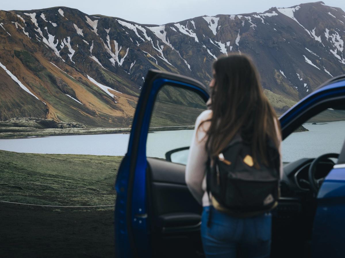 Puerta Lakeside para Mitsubishi Eclipse Cross Mitsubishi Eclipse Cross con la puerta abierta y una persona de pie junto a un lago y unas montañas