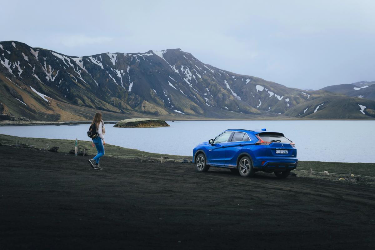 Mitsubishi Eclipse Cross aparcado cerca de un lago, con montañas al fondo y una persona caminando por los alrededores