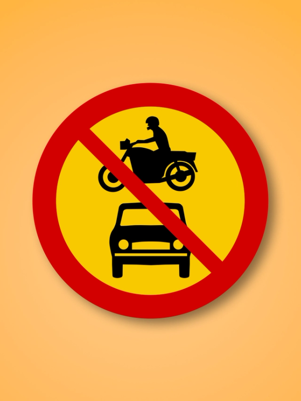 Red and yellow circle road sign with a rental car and a motorcycle in the middle. This road sign means No Motor Vehicles can enter.