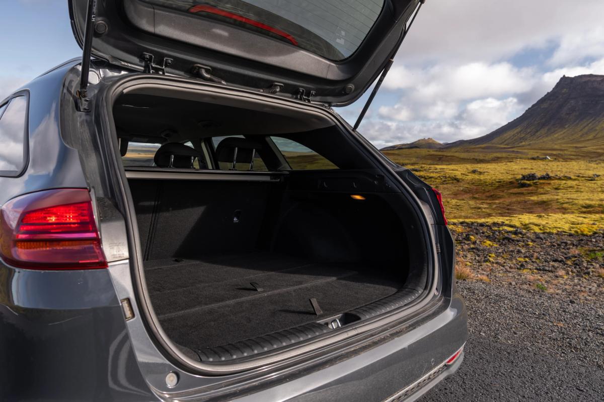 Kia Ceed familiar con el portón trasero abierto y un paisaje montañoso de fondo