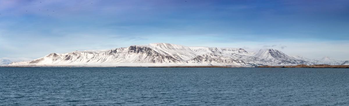 a snowy mountain rises over a body of water .