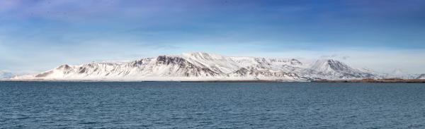 a snowy mountain rises over a body of water .