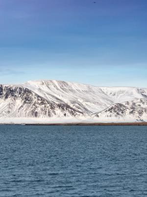 a snowy mountain rises over a body of water .