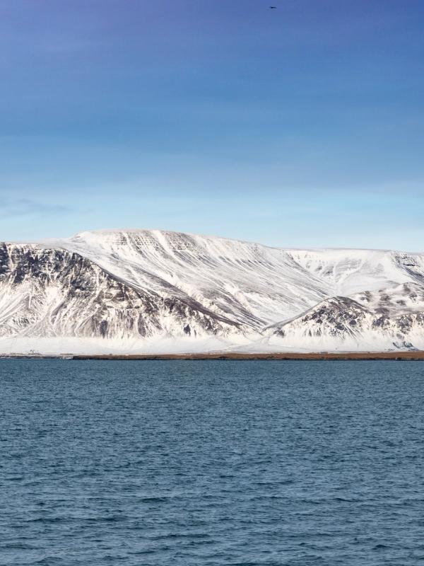 a snowy mountain rises over a body of water .