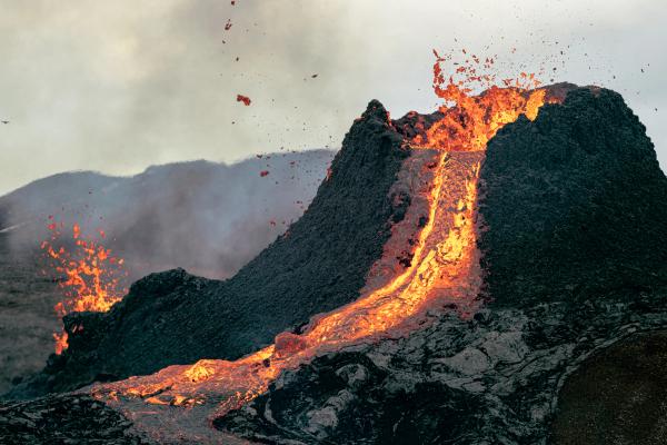 a volcano is erupting and lava is coming out of it .