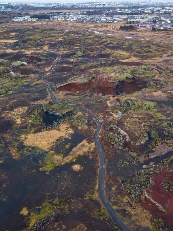 an aerial view of a road going through a lush green field .