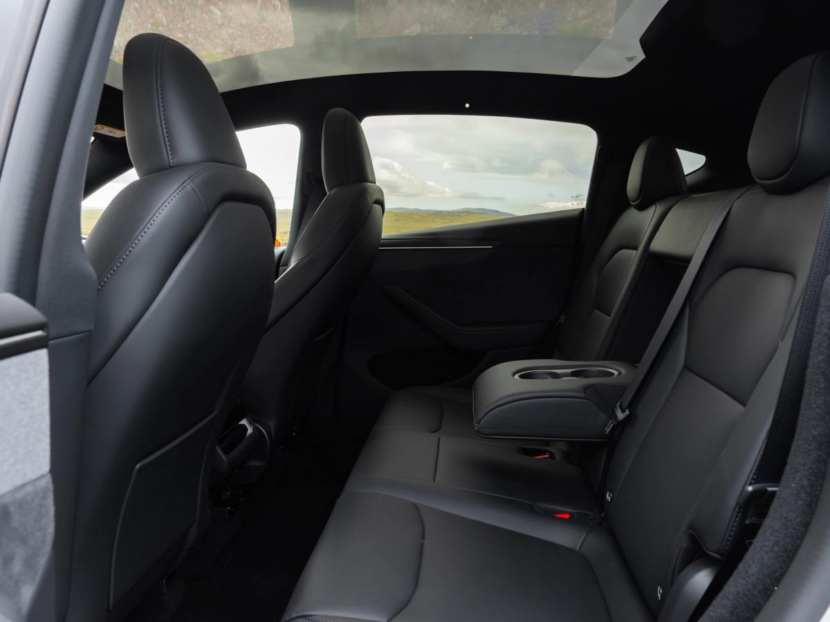 Asiento trasero tipo banco Asientos traseros del Tesla Model Y con reposabrazos central y portavasos, espacioso coche eléctrico de alquiler en Islandia