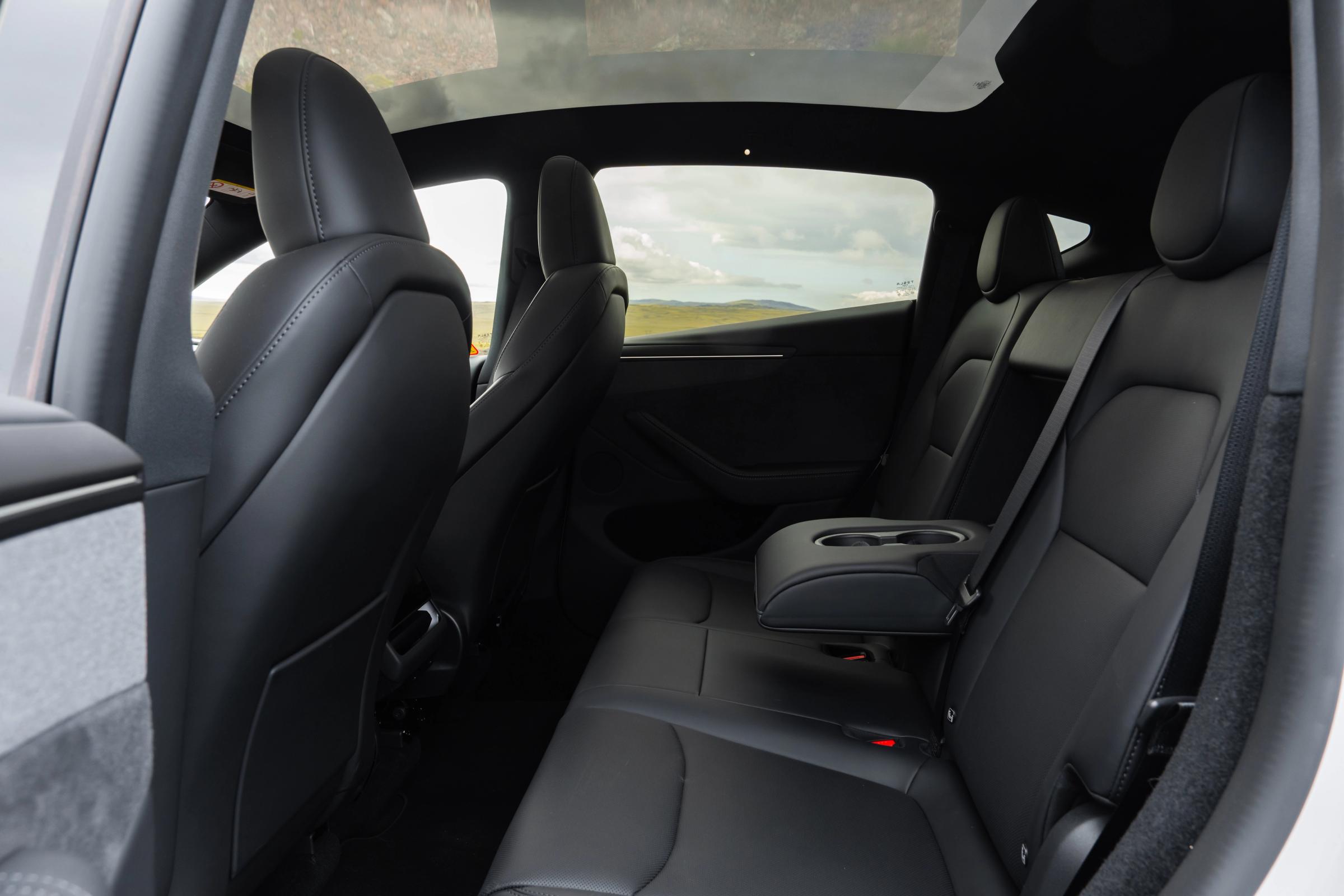 Asiento trasero tipo banco Asientos traseros del Tesla Model Y con reposabrazos central y portavasos, espacioso coche eléctrico de alquiler en Islandia