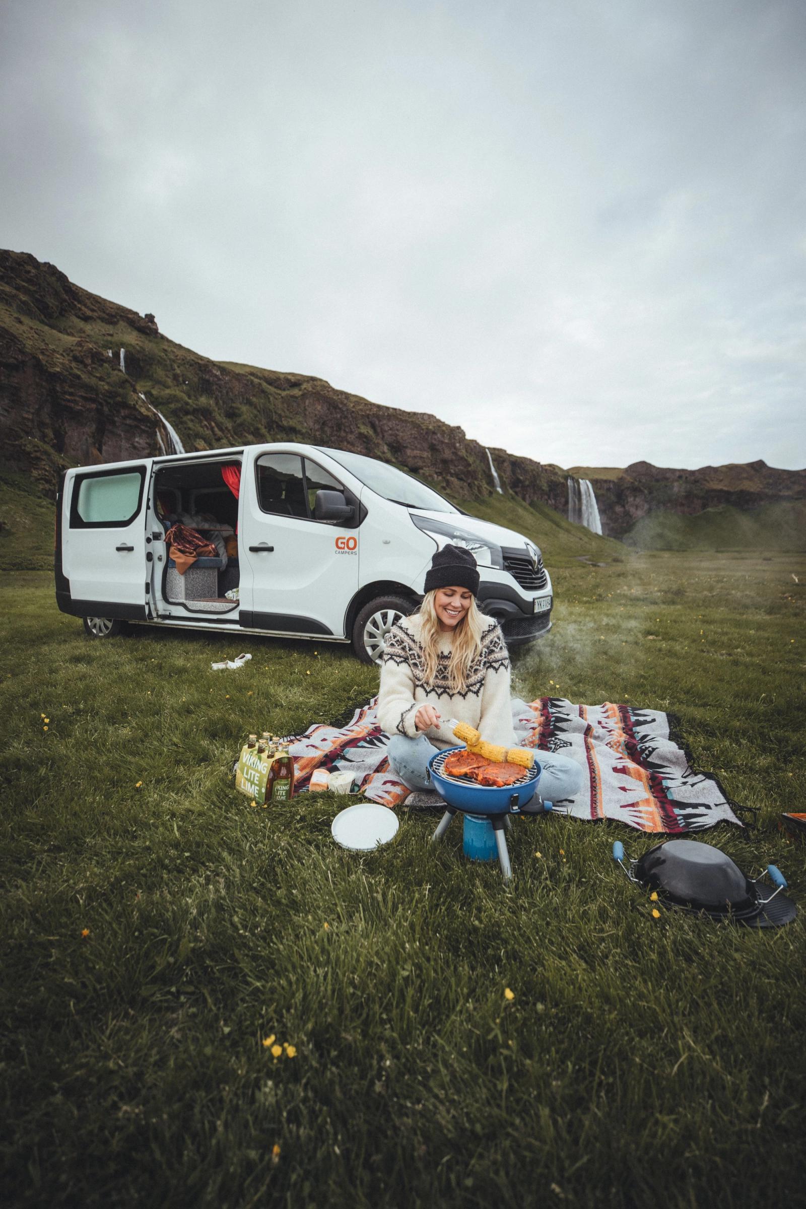 Girl camping and cooking food outside of her car rental in Iceland