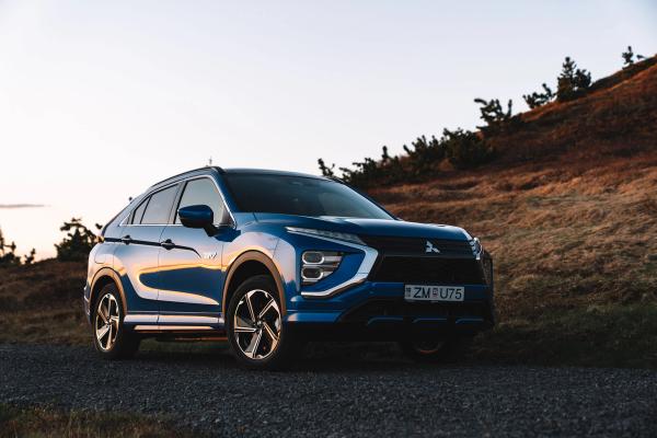 a blue mitsubishi eclipse cross is parked on the side of a dirt road .