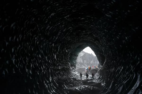 un grupo de personas camina a través de una cueva oscura .
